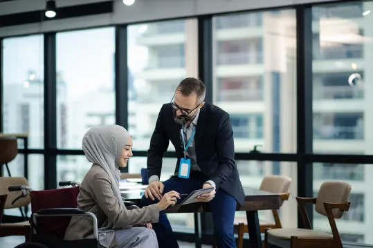 woman in headscarf and man looking at ipad